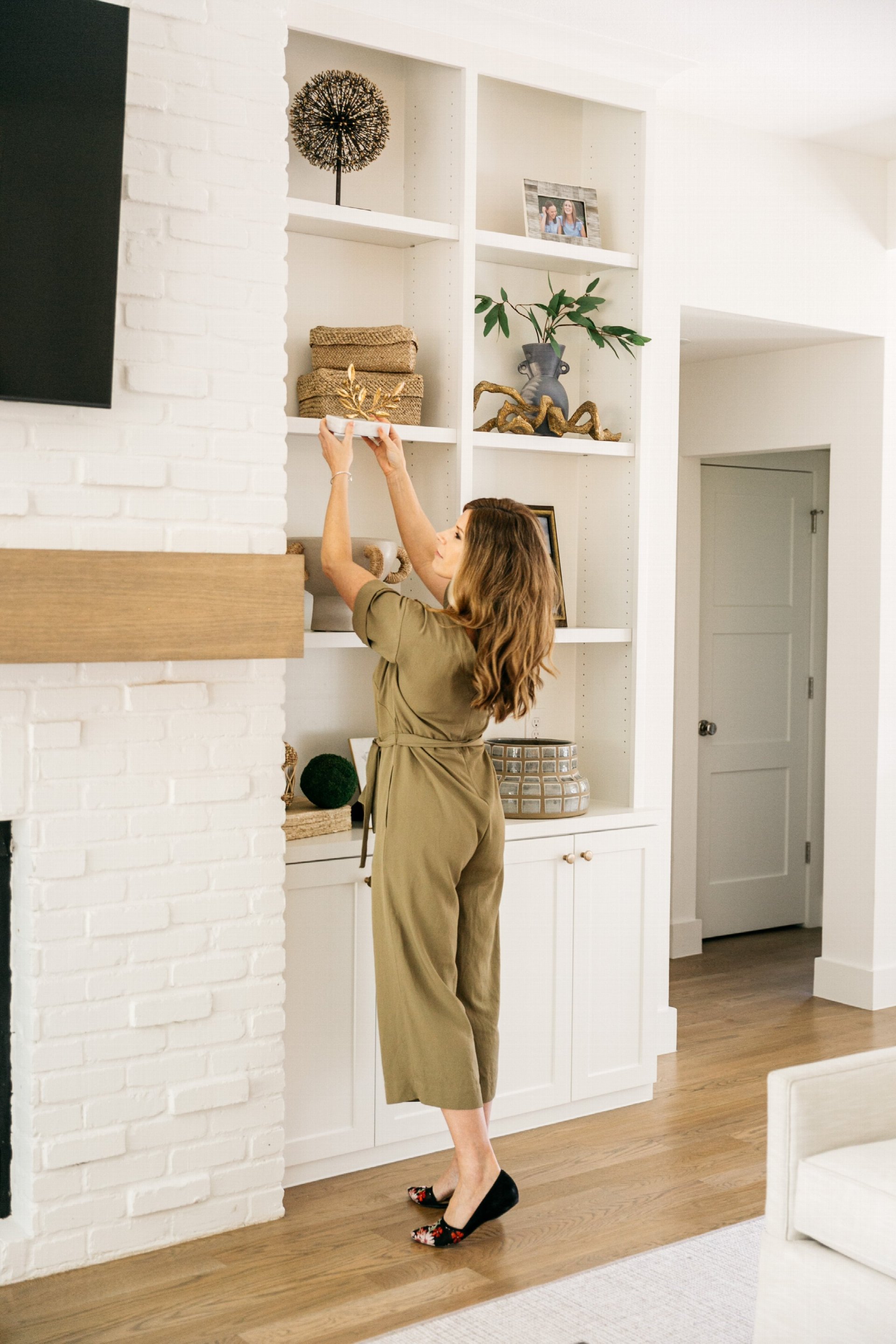 Sara Carroll styling built-in shelving in a luxury living room, showcasing curated decor and refined interior design.