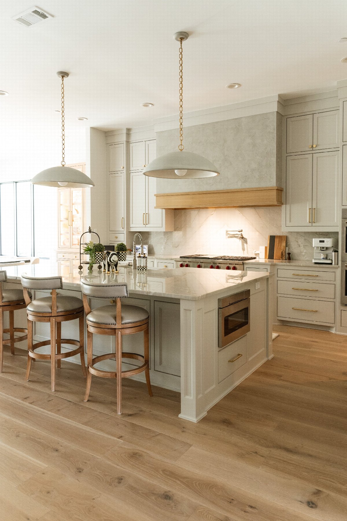 Luxury kitchen with large island, custom cabinetry, pendant lighting, and bar seating in a bright, open-concept interior design.